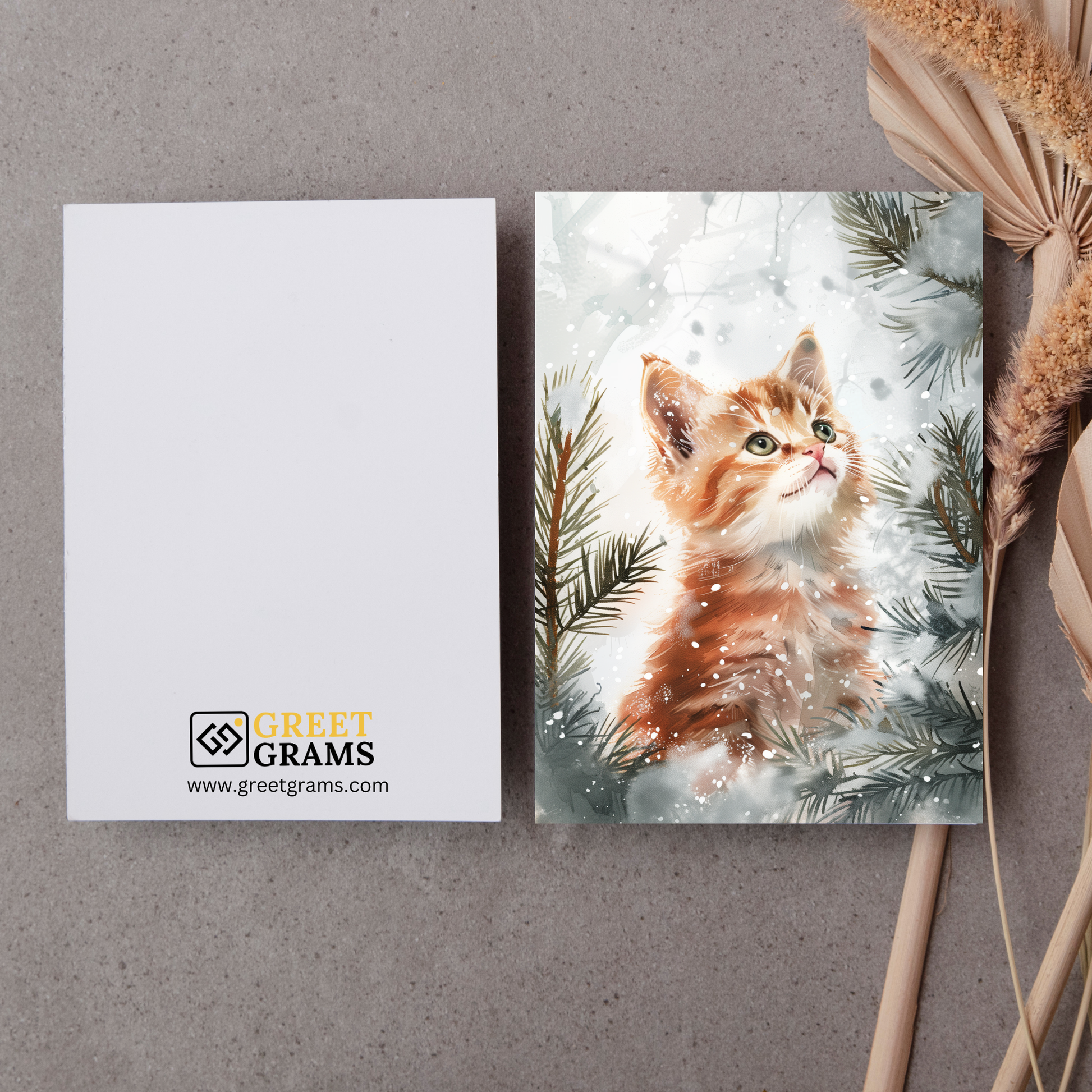 greeting card of a Kitten in the snow with tress with the grey background